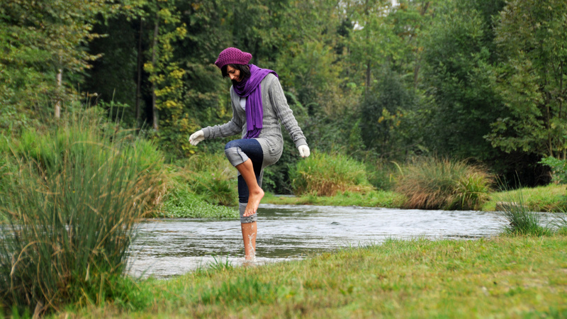 Wellness, Kneippen, Wassertreten: Frau kneippt im Grünen
