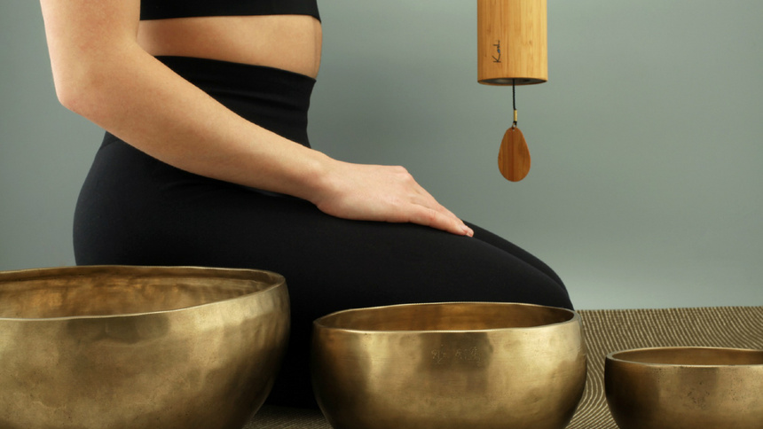 Tibetische Medizin, Naturheilverfahren, Heilmethoden: Eine Frau kniet hinter drei Klangschalen.