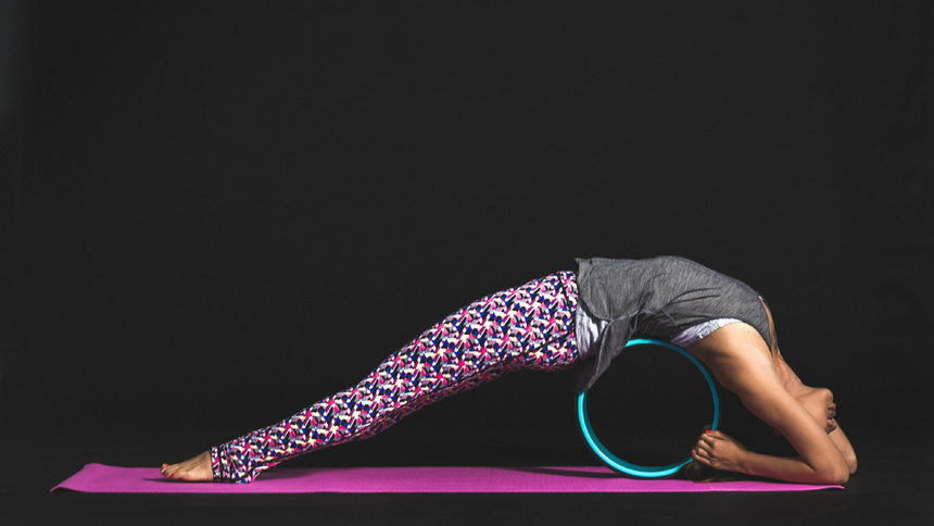 Une jeune femme fait un pont arrière autour d'un accessoire de fitness