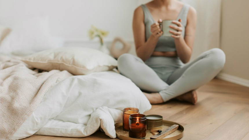 Psychologie, Stress, Entspannen, Abschalten: Eine Frau sitzt in einem Raum, mit einer Tasse in der Hand und einem Tablett mit Tee vor sich.