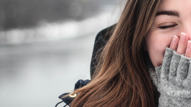 Eine Frau hält ihre Hände vor die Nase und den Mund. 