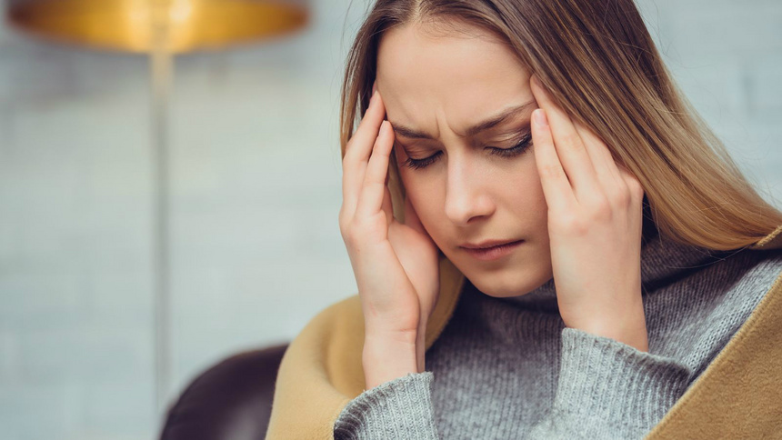 Kopfschmerzen, Clusterkopfschmerzen: Eine Frau stützt das Gesicht in die Hände und hält sich den Kopf