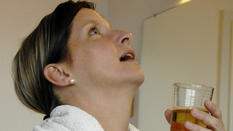 Refroidissements maux gorge déglutition: une femme est en train de se gargariser. Elle a la tête en arrière.