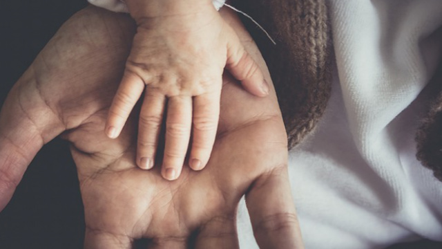 Die Hand eines Babys liegt auf der Hand eines Erwachsenen.
