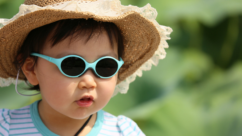 Un petit enfant avec un chapeau de paille et des lunettes de soleil