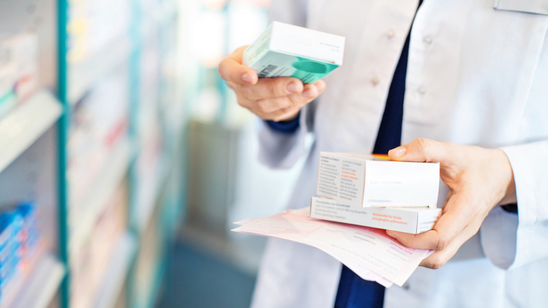 Eine Drogistin hält in ihren Händen Medikamenten-Packungen.