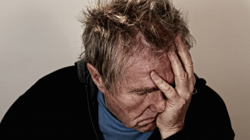 Un homme se tient la tête. Il a l'air d'avoir mal.