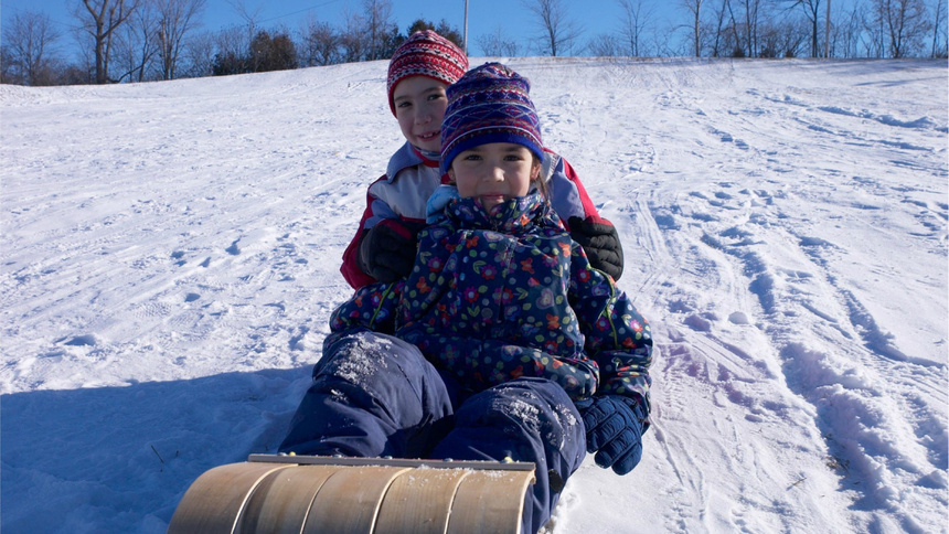 Deux enfants sont assis sur une luge en bois