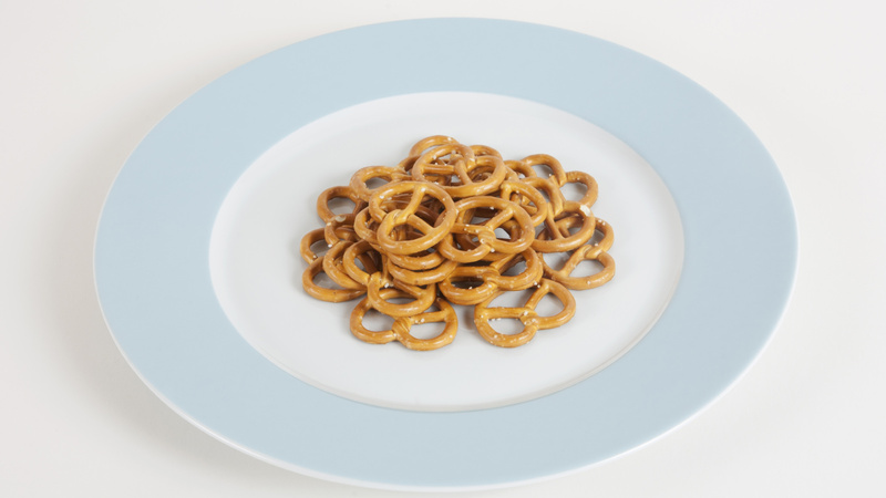 Un tas de bretzels salés posés sur une assiette blanche avec un bord bleu clair