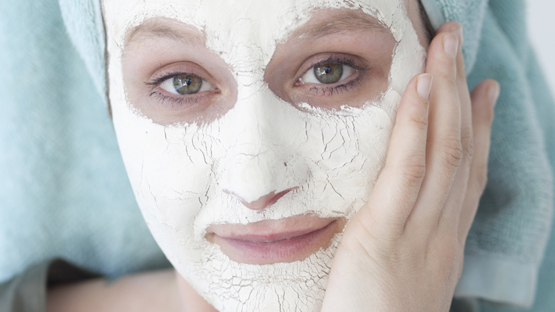 Une femme s'applique un masque sur le visage