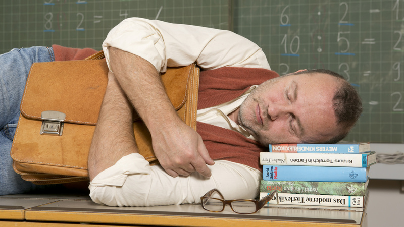Alimentation détoxination cure signaux alarme: un homme couché de côté dort sur un banc d'école, la tête posée sur une pile de livres.