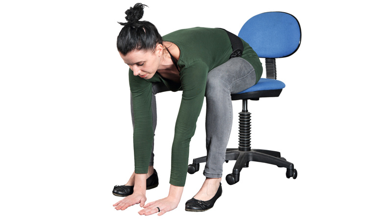 Une femme assise sur une chaise se baisse pour toucher le sol avec ses mains