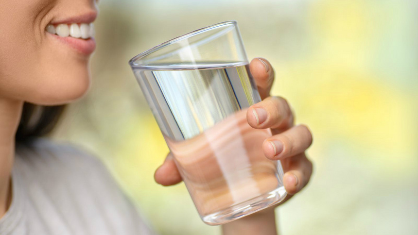Alimentation détoxination règles à respecter: gros-plan sur une femme qui boit un verre d'eau.