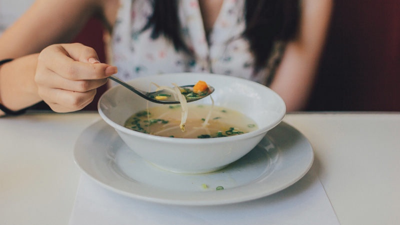 Une femme mange une soupe avec des germes de sola