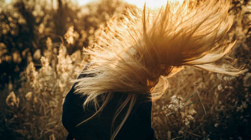 Une femme avec de longs cheveux blonds qui sont agités par le vent