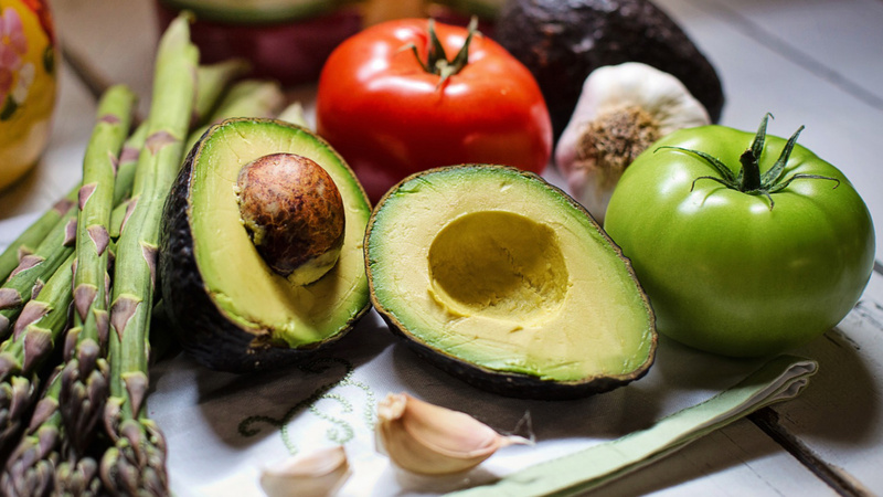 Ernährung, Gemüse, Lagern, Zubereiten: Tomaten, Spargeln, Knobli und Avocados liegen auf dem Tisch.