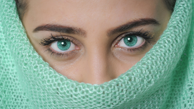 Fieberbläschen, Herpes, Küssen: Junge Frau hat Mund und Nase mit einem türkisfarbenen Wollschal verdeckt