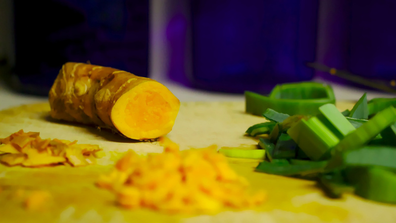 Alimentation épices curcuma force: une racine de curcuma sur une planche avec un petit tas de curcuma émincé et un autre en fines tranches.