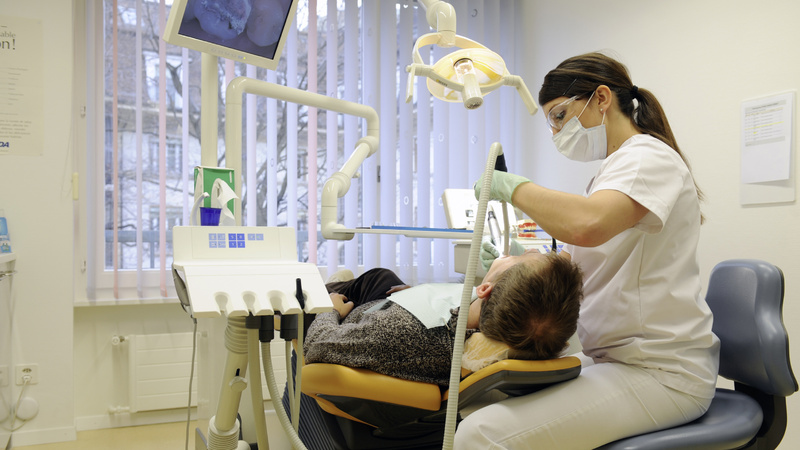 Une hygiéniste nettoie les dents d'un patient couché