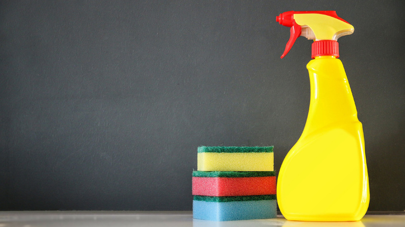 Wohngifte, Putzmittel, Chemikalien: Gelbe Sprühflasche steht neben drei aufeinandergeschichteten Putzschwämmen. Die Schwämme sind blau, rot und gelb.