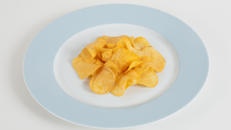 Une assiette blanche avec un bord bleu clair qui contient un petit tas de chips.