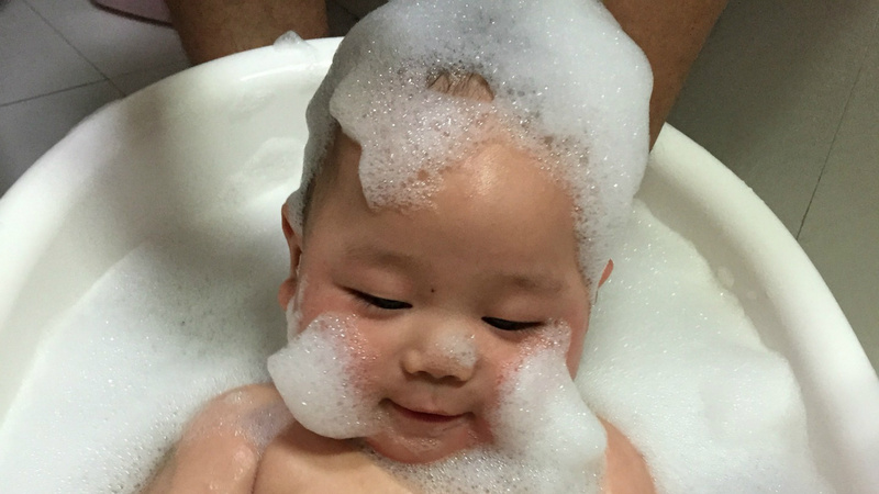 Un bébé dans une baignoire avec les cheveux pleins de mousse