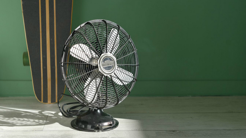 Ein schwarzer Ventilator. Der Hintergrund ist grün.