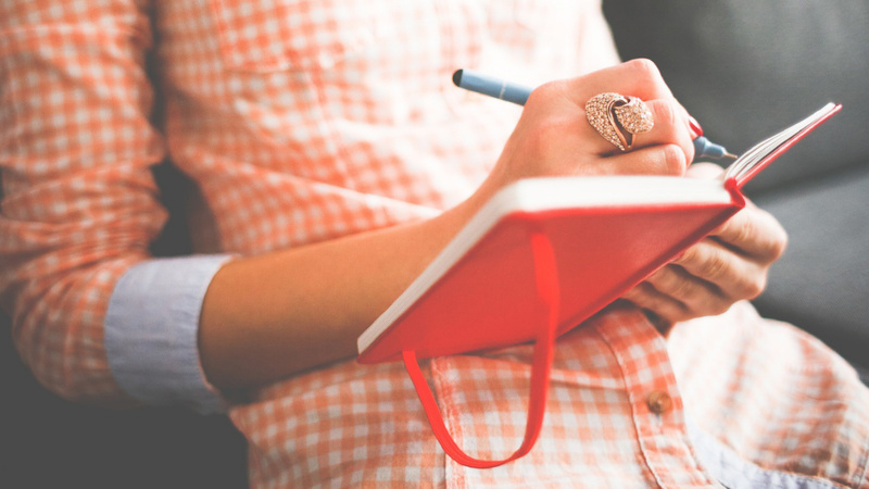 Gros-plan sur une main de femme qui écrit dans un journal