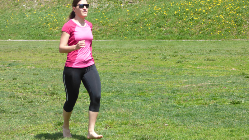 Une jeune femme court pieds nus dans un pré