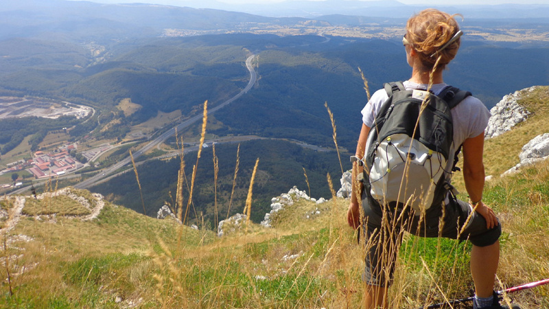 Une femme est au sommet d'une montagne. Elle regarde vers la plaine.