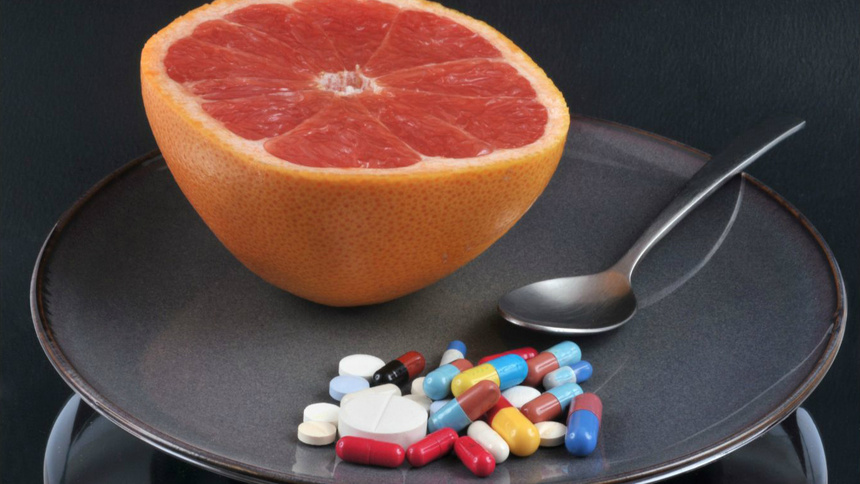 Medikamente, Wechselwirkung, Arzneimittel: Eine halbe Grapefruitscheibe vorne mehreren Tablettenblistern