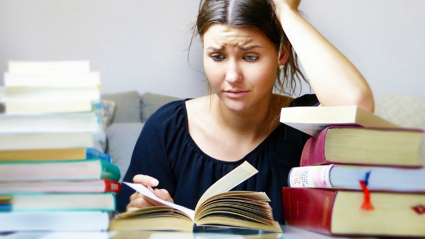 Une jeune fille est assise à son bureau. Elle a devant elle un livre ouvert et elle a l'air désespérée. 