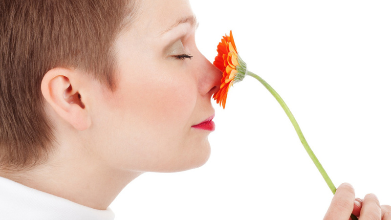 Une femme sent une fleur.