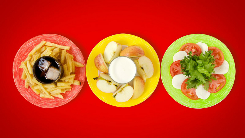Ernährung, gesund: Drei Teller: ein roter mit Pommes frites, ein gelber mit Äpfeln und Joghurt und ein grüner mit Tomate-Mozzarella-Salat.