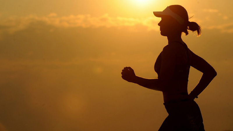 Une femme court dans un coucher de soleil.