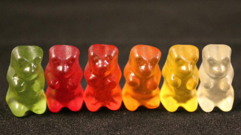 Ernährung, Zusatzstoffe, Farbstoffe: Gummibärchen sitzen nebeneinander. Von links: grün, rot, hellrot, orange, gelb und weiss