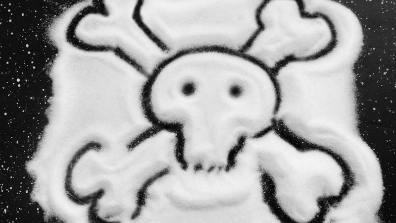 Ernährung, Salz: auf eine schwarze Unterlage ist Salz verstreut, darin gezeichnet ein Totenkopf