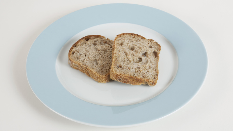 Deux tranches de pain complet posées sur une assiette blanche avec un bord bleu clair