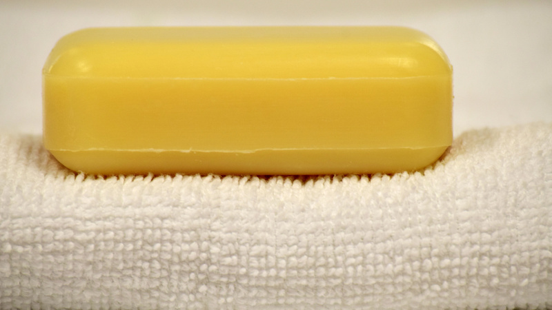 Schönheit, Pflege, Sauberkeit: Ein Stück gelbe Seife liegt auf einem weissen zusammengefalteten Frotteetuch