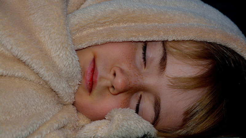 Ein Kind, in eine Decke eingewickelt, schläft