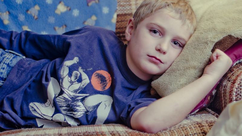 Un garçon est couché sur un canapé.