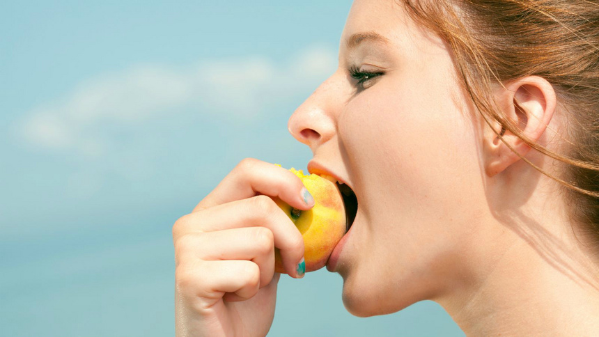 Alimentation régimes astuces limitation calories: Une femme qui croque dans une pomme