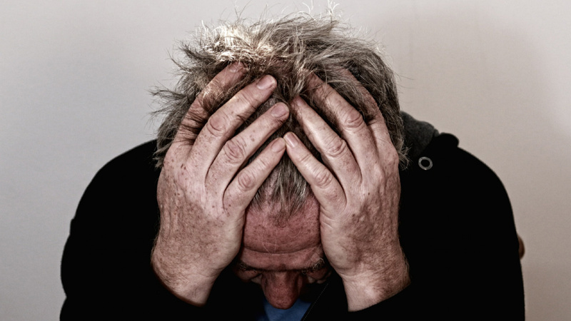 Psychologie épuisement conseils lutte: un homme se tient le crâne à deux mains. Il a l'aur épuisé.