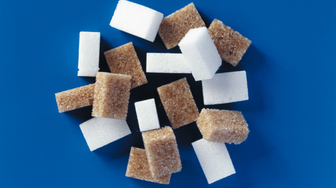 braune und weisse Würfelzucker auf blauem Grund