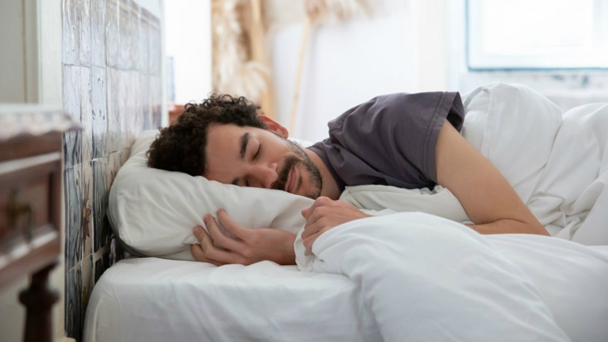 Schlafen, Einschlafen, Schlafapnoe: Ein Mann, der auf der Seite in einem Bett schläft