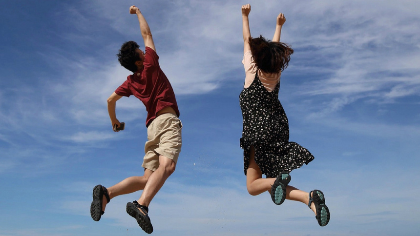 Une femme et un homme sautent en l'air avec le ciel bleu en arrière-plan