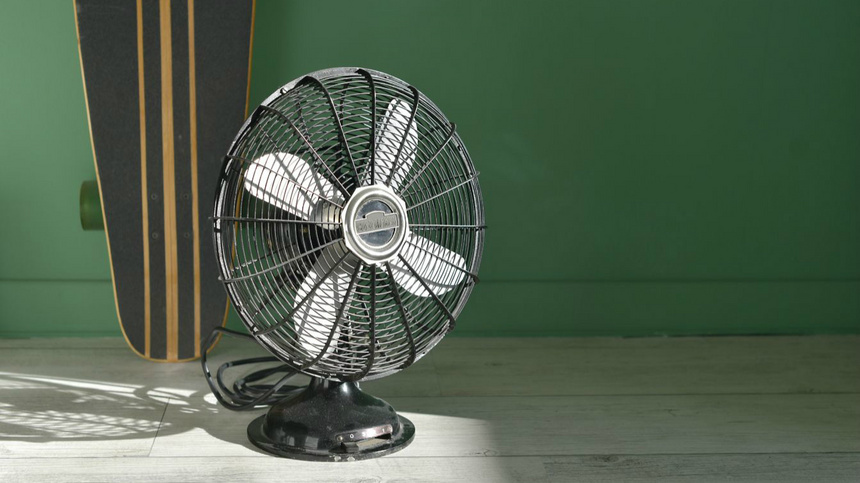 Un ventilateur noir sur un arrière-plan vert.