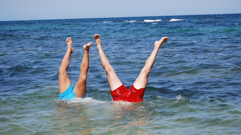 Körper, Venen, Gymnastik: Meer, die Beine von zwei Männern, die kopfüber im Wasser stehen