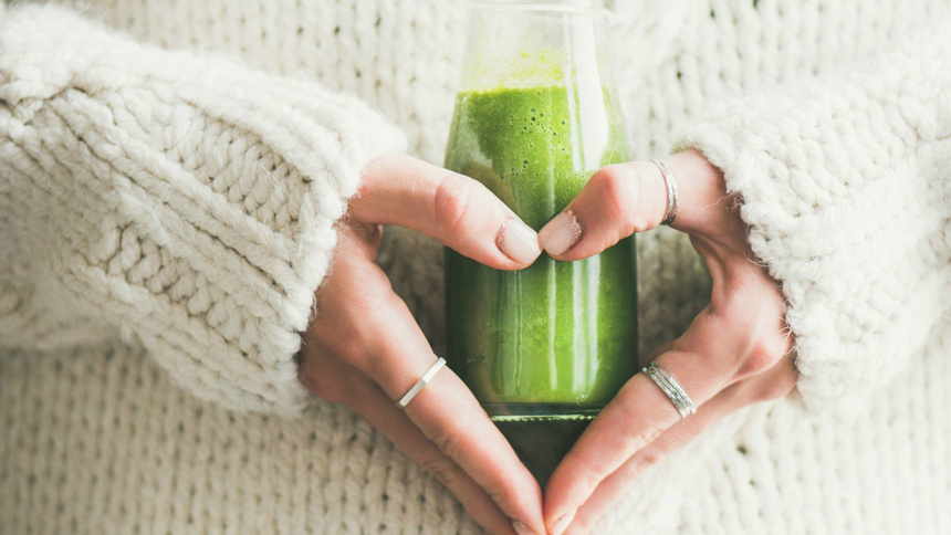 Alimentation détoxination connaissances explications: un ventre de femme. Ses deux mains forment un cœur sur son ventre avec un smoothie