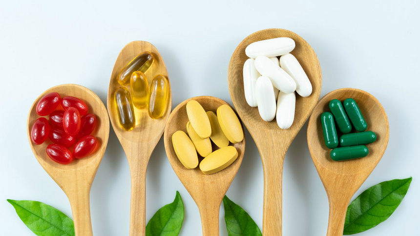 Alimentation vitamines compléments: plusieurs cuillières avec des gelules de vitamine de couleurs différentes